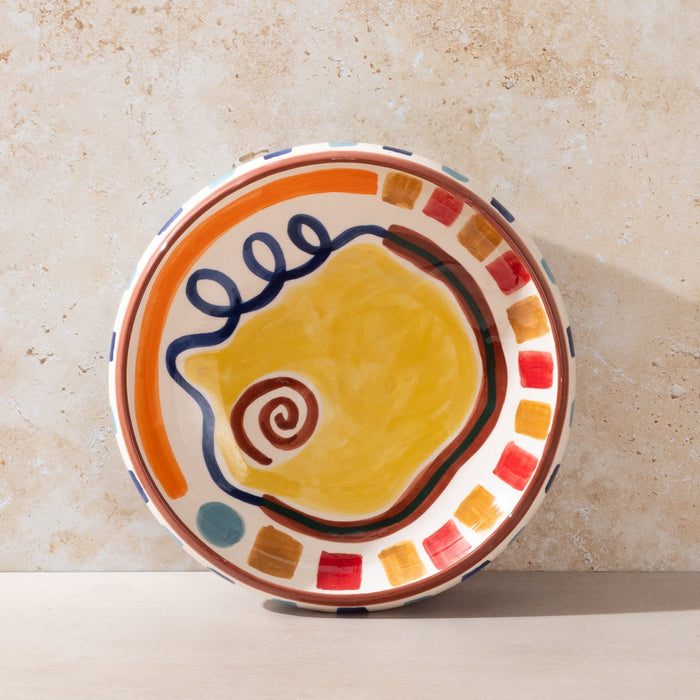 Ceramic LRNCE bowl with colorful design on a beige surface