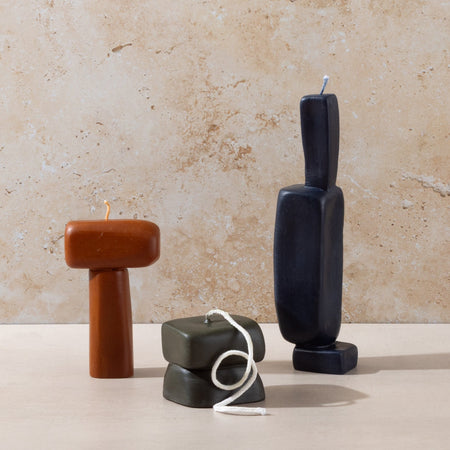 Three sculptural Mulier candles on natural stone background