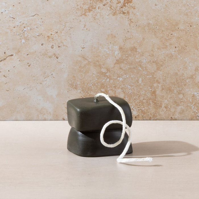 Three sculptural Mulier candles on natural stone background