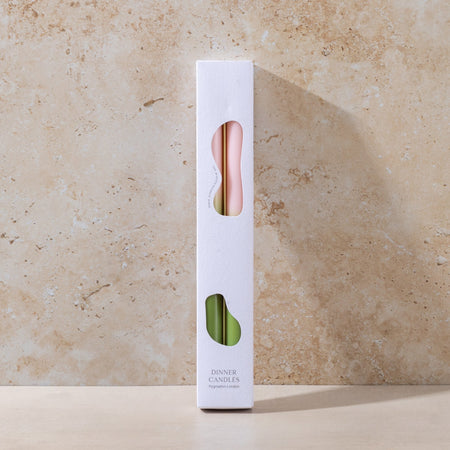 White candle packaging with a pink wick on a beige stone background