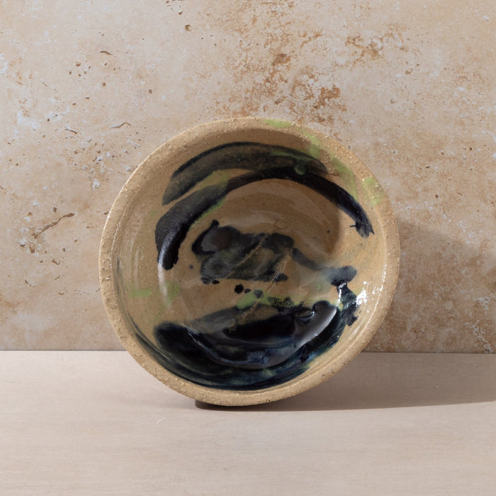 Ceramic bowl with a black design on a beige surface