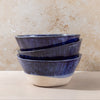 Stack of blue ceramic bowls on a beige surface with a textured beige wall background