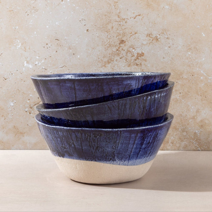 Stack of blue ceramic bowls on a beige surface with a textured beige wall background