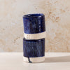 Two blue ceramic cups stacked on a beige surface with a textured wall background