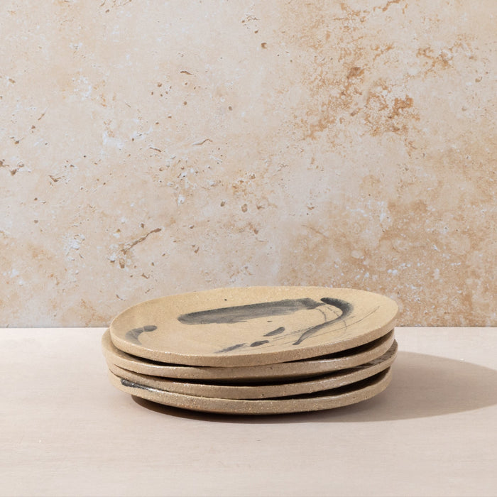 Stack of ceramic plates with a fish design on a beige surface and background