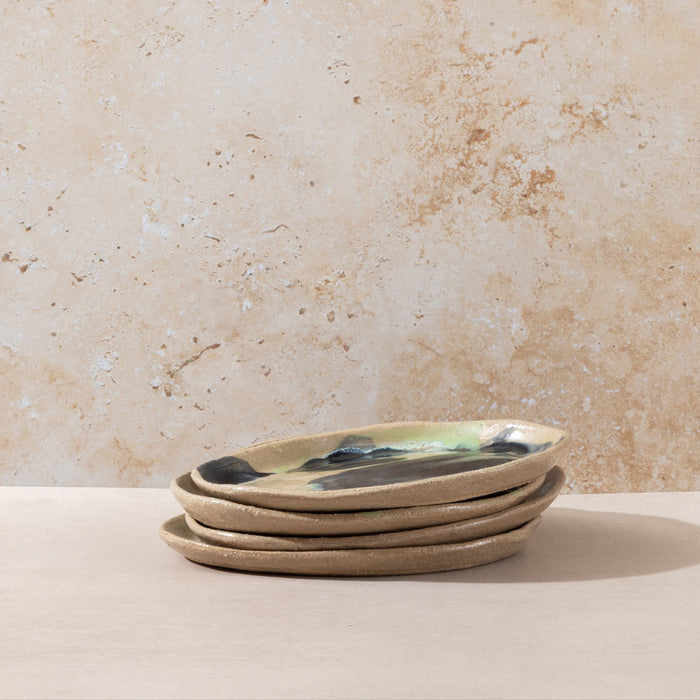 Stack of ceramic plates with a natural finish on a beige surface with a textured wall background