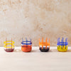 Four colorful glass tumblers on a light surface with a beige background