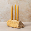 Three yellow candles in a stone holder against a beige background