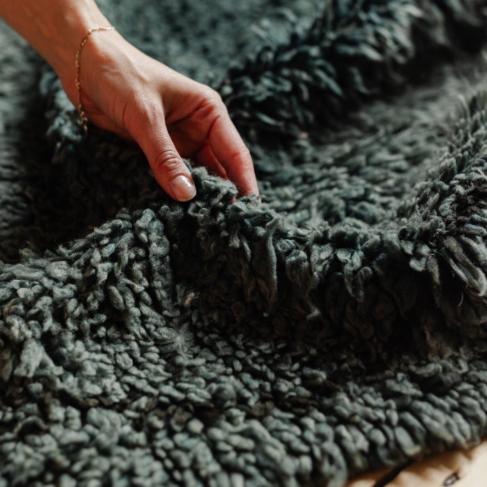 Moroccan Berber rug with black diamond pattern on blue / grey base in a modern boho rustic earthy interior, on a wooden floor