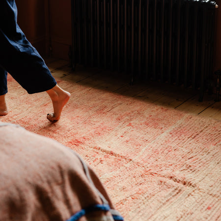 Person walking on a soft pink ombre Moroccan Boujad vintage rug in a cosy modern boho interior.