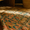 Close-up of a vintage Moroccan pink Berber rug with geometric pattern on a wooden floor.