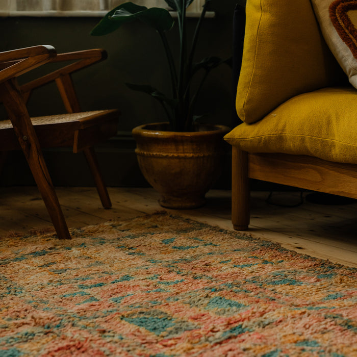 Cozy living room corner with a yellow sofa, wooden chair, and patterned vintage Moroccan Berber rug.