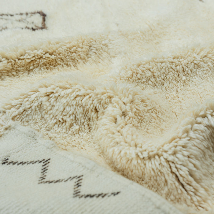 Colse up of Moroccan Beni Ourain rug with berber symbols in washed black on a luxurious cream wool base. 