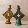 Two green moroccan tamegroute candle holders with cross designs on a beige background