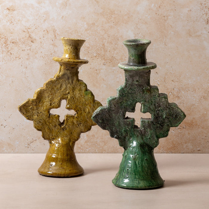 Two green moroccan tamegroute candle holders with cross designs on a beige background