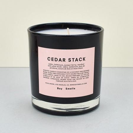  ‘Cedar Stack’ scented candle by Boy Smells. Black candle with a light pink label. 