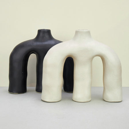 two sculptural ceramic vases, in black and white across a plain background. 