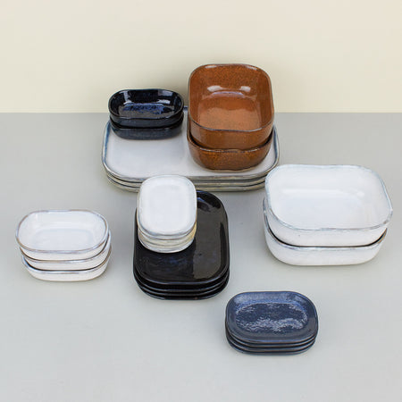 ceramic shallow plates and deeper dishes in white, black, blue and brown. 
