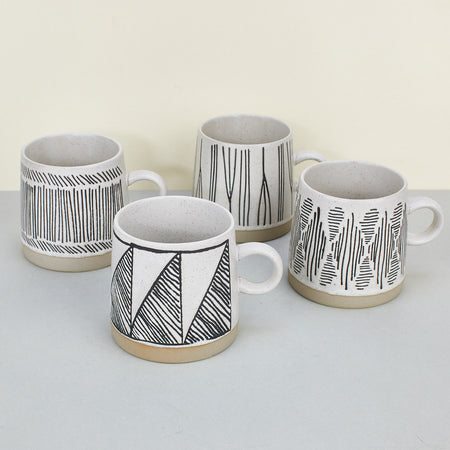 Ceramic mugs with cream glaze with etched patterns in dark brown 