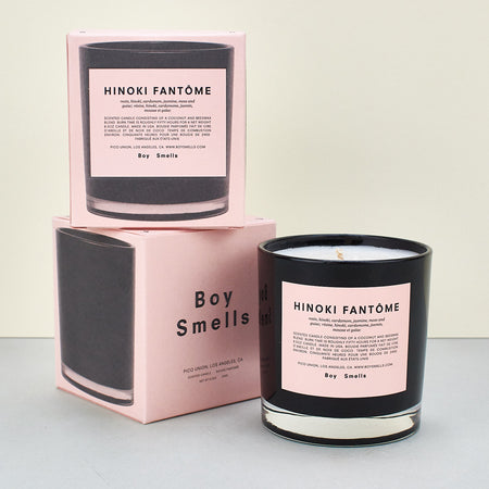 black candle with a pink label and text across a plain background. candle box in pink with an image of the candle. 