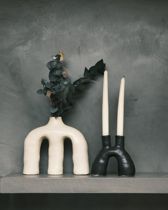 two sculptural ceramic vases, in black and white on a table with a grey backdrop. 