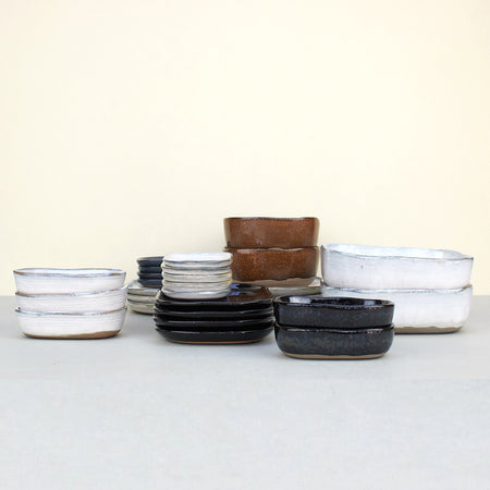 ceramic shallow plates and deeper dishes in white, black, blue and brown. 