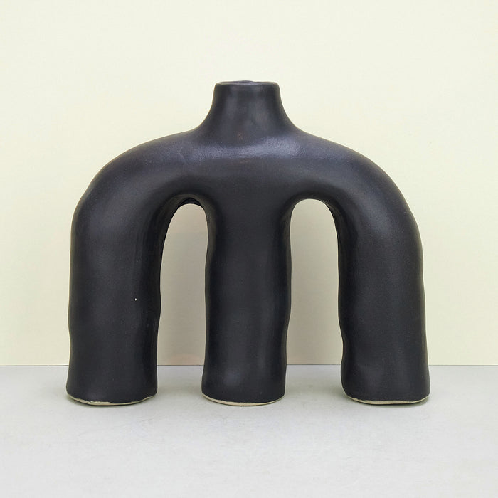 sculptural ceramic black vases across a plain background. 