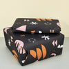 gifts wrapped in black gift wrapping paper with orange and pink patterns, a new tribe logo 