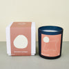 moroccan black candle with a pink label with an outline of morocco. next to a white candle box with a pink cover. 