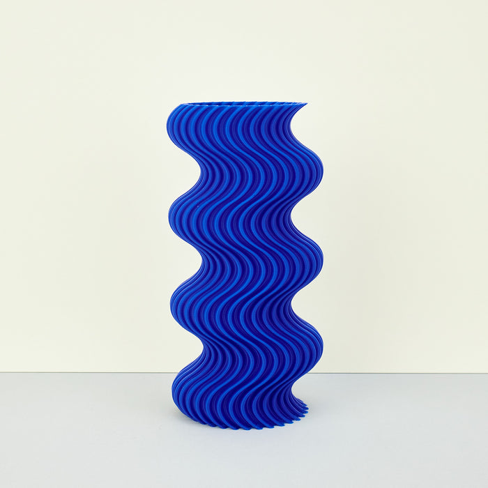blue colourful ribbed wavy vase on a plain background. 