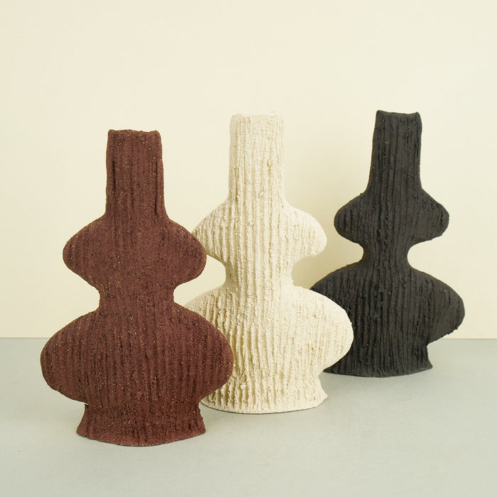 ribbed ceramic clay vases in brown, beige and grey on a plain background