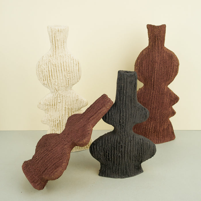 ribbed ceramic clay vases in brown, beige and grey on a plain background