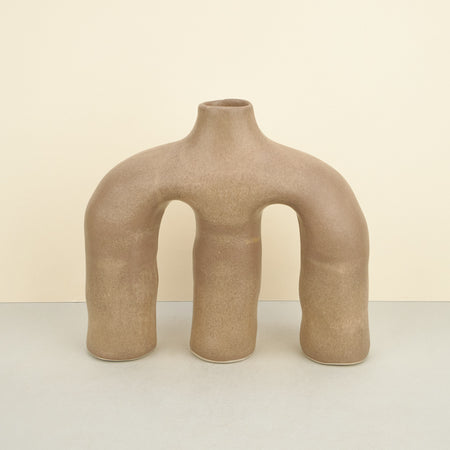sculptural ceramic beige vases across a plain background. 
