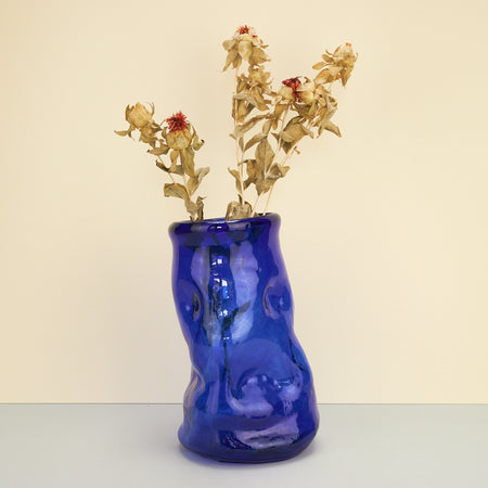Limited edition cobalt blue glass vase by Kana London. Vase on a plain background with dried flowers.