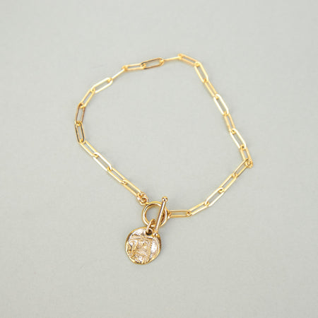 gold bracelet with round pendant. 