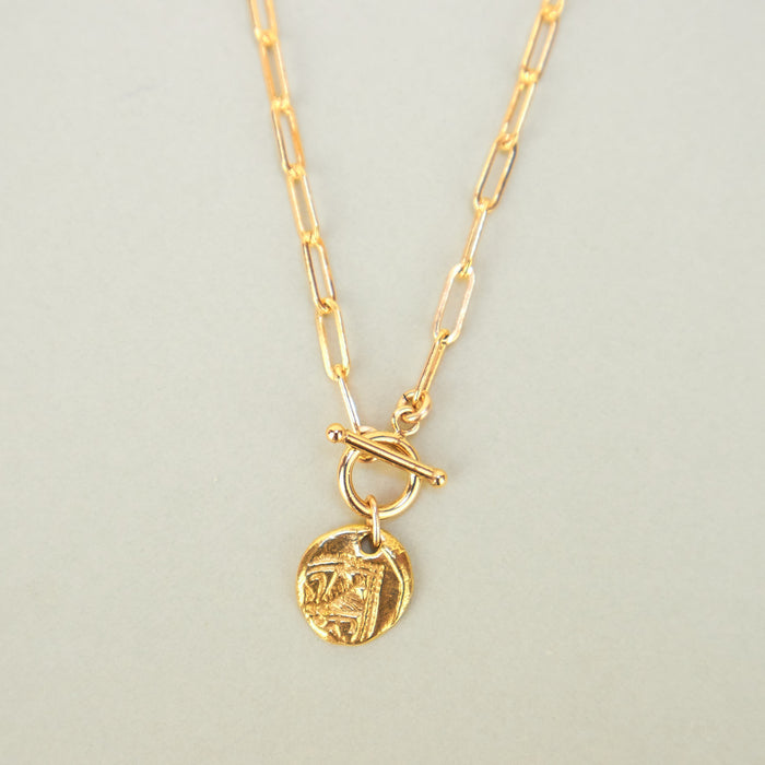 gold necklace with round pendant. 