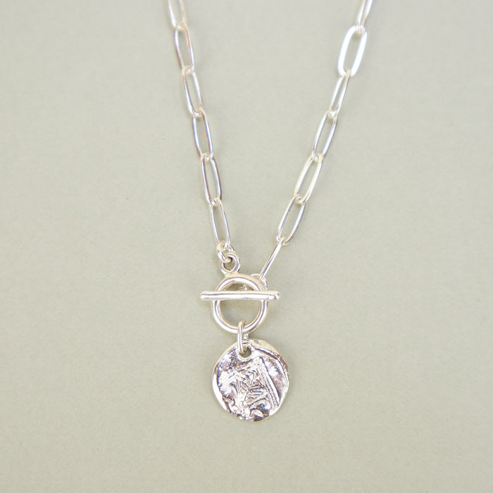 silver necklace with round pendant. 