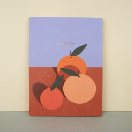 notebook with illustrated oranges on an orange table with a blue background. notebook on plain background. 