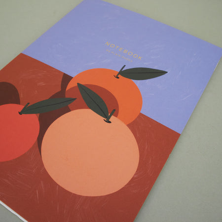 notebook with illustrated oranges on an orange table with a blue background. notebook on plain background. 