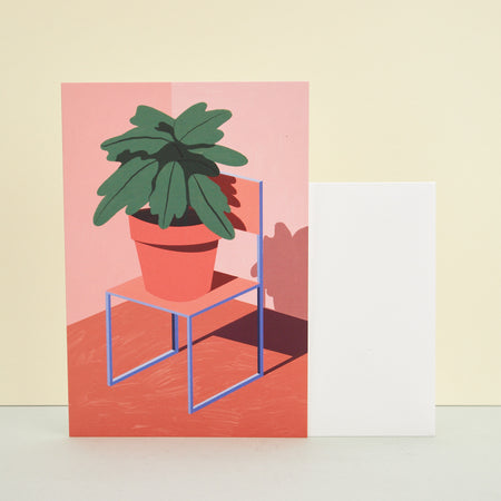 card with illustration of a plant on a chair in orange hues