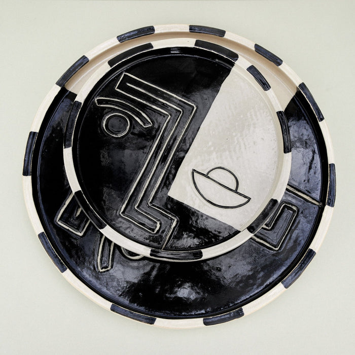 black and white plates with faces on them in a geometric manner. 